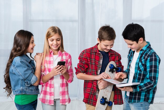 Bambini ad alto angolo con skateboard e telefono