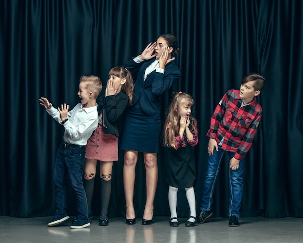 Bambini alla moda carino in studio scuro. belle ragazze adolescenti e ragazzo in piedi insieme