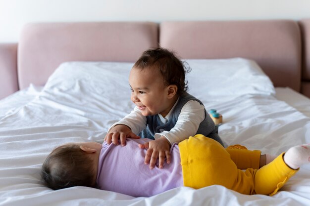 Bambini carini che giocano tra loro sul letto