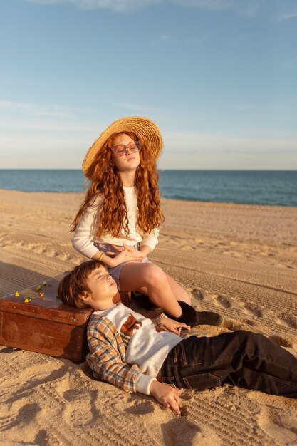 Bambini carini con con la valigia sulla spiaggia