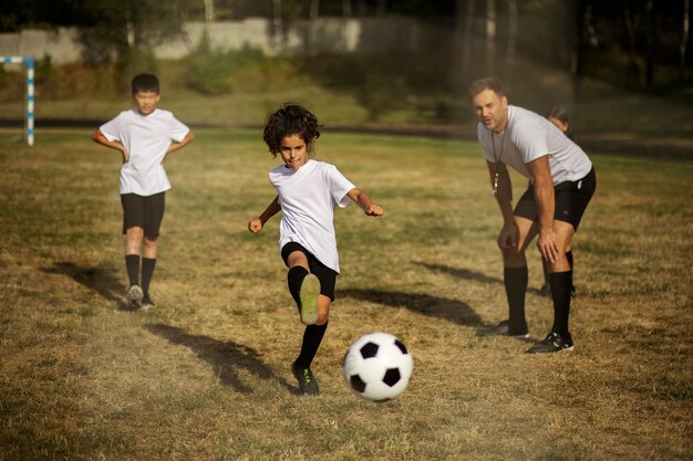 Bambini che giocano a calcio sotto la supervisione di un allenatore di calcio