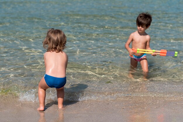 Bambini che giocano con pistole ad acqua in spiaggia