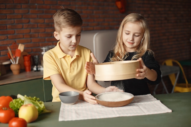 Bambini che giocano con una farina in una cucina