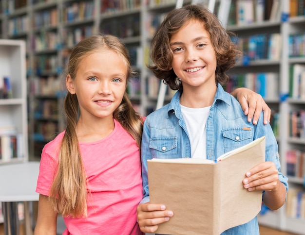 Bambini che leggono un libro insieme in biblioteca