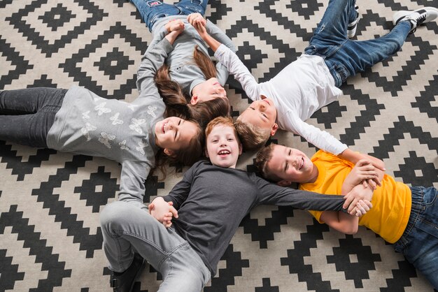 Bambini che posano insieme posa sul pavimento