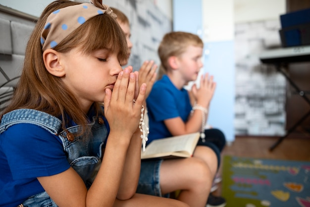 Bambini che pregano insieme alla vista laterale della scuola domenicale