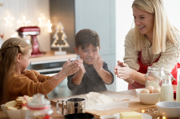 Bambini che stringono usando la farina mentre cuociono i biscotti