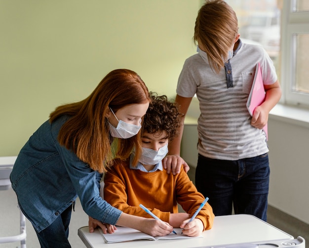 Bambini con maschere mediche che imparano a scuola