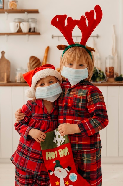 Bambini con mascherina medica in possesso di un calzino di Natale