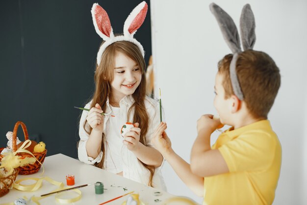 Bambini con orecchie da coniglio. Uova di Pasqua dipinte. Bambini con colori e pennelli.