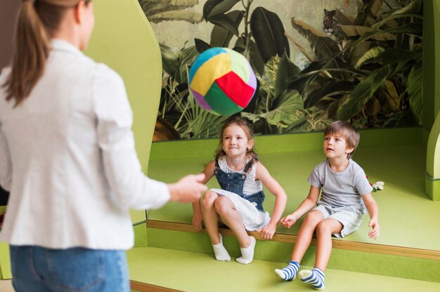 Bambini del primo piano e insegnante che giocano con la palla