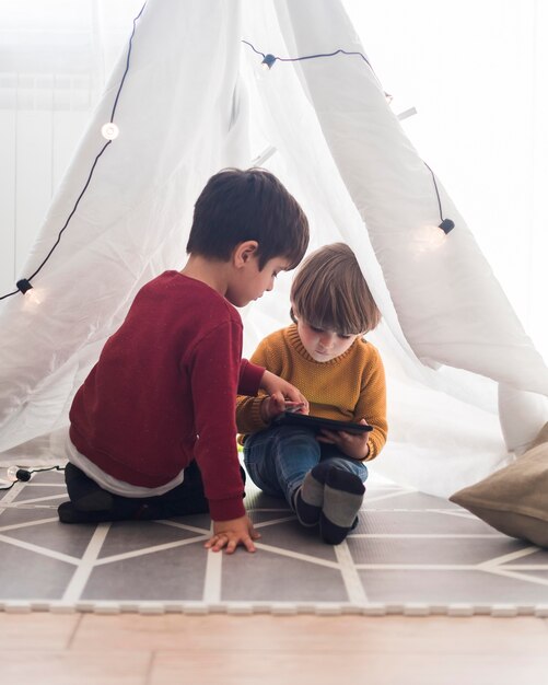 Bambini della foto a figura intera in tenda fatta in casa