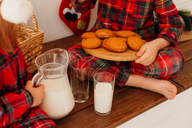 Bambini di alto angolo che mangiano i biscotti di Natale e che bevono latte