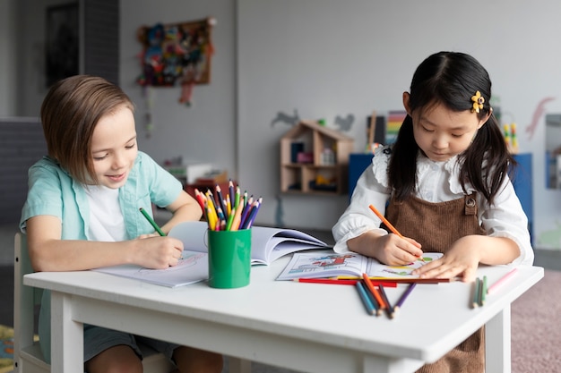 Bambini di tiro medio che colorano a tavola