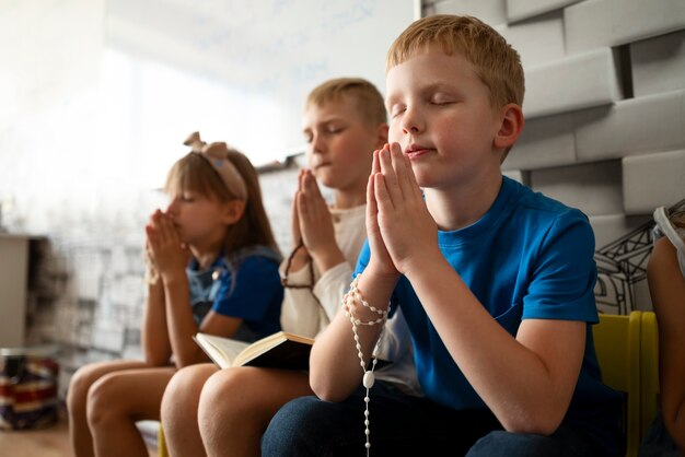 Bambini di tiro medio che pregano insieme alla scuola domenicale