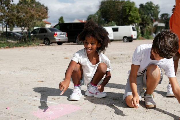 Bambini di vista frontale che disegnano sul marciapiede