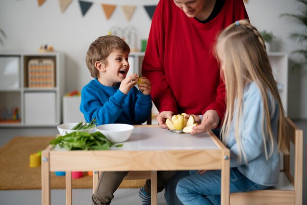 Bambini di vista laterale che guardano l'insegnante taglia la mela