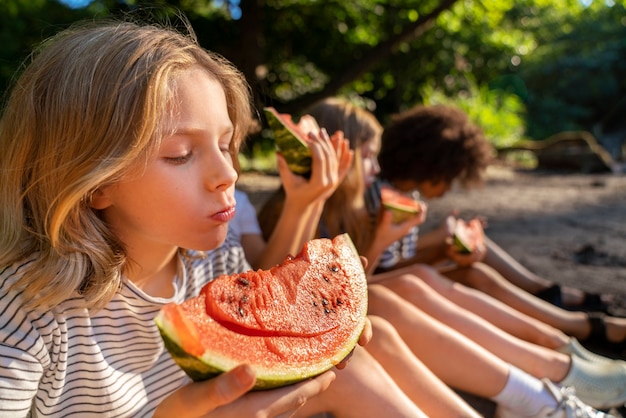 Bambini di vista laterale che mangiano l'anguria