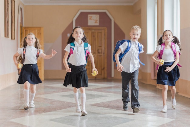 Bambini divertenti con mele nel corridoio della scuola