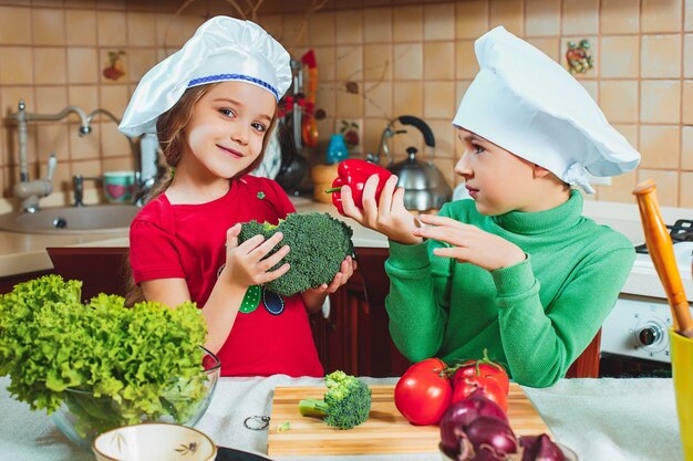 Bambini divertenti famiglia felice stanno preparando un'insalata di verdure fresche in cucina