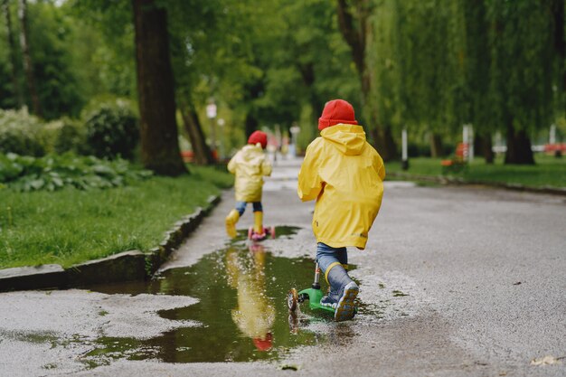 Bambini divertenti in stivali da pioggia che giocano con i pattini