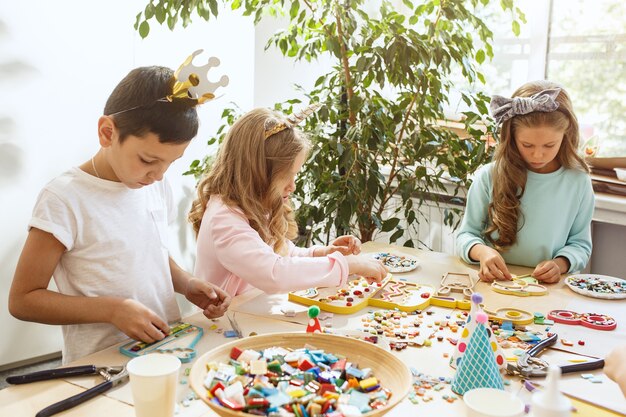 bambini e decorazioni di compleanno. ragazzi e ragazze a tavola con cibo, dolci, bevande e gadget per le feste.