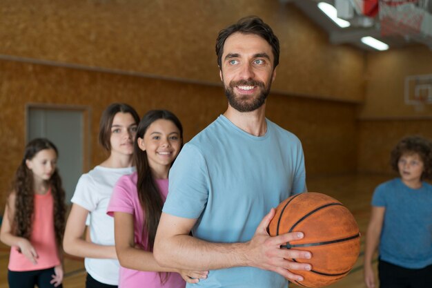 Bambini e insegnante con palla da basket a tiro medio