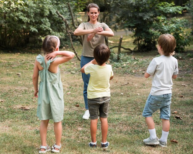 Bambini e insegnante del colpo pieno che giocano all'aperto