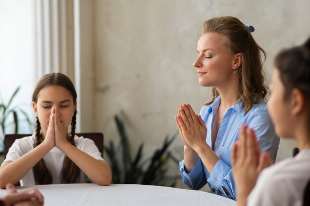 Bambini e insegnante di vista laterale che pregano insieme