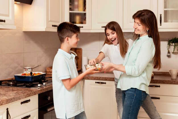 Bambini e madre che preparano cibo in cucina