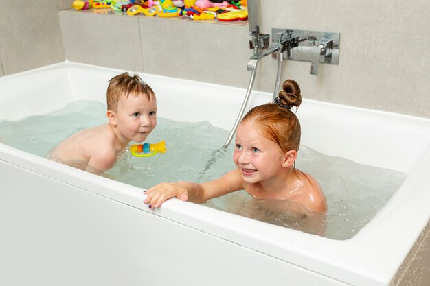 Bambini felici che giocano nella vasca da bagno