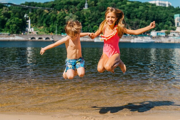 Bambini felici che saltano alla linea costiera