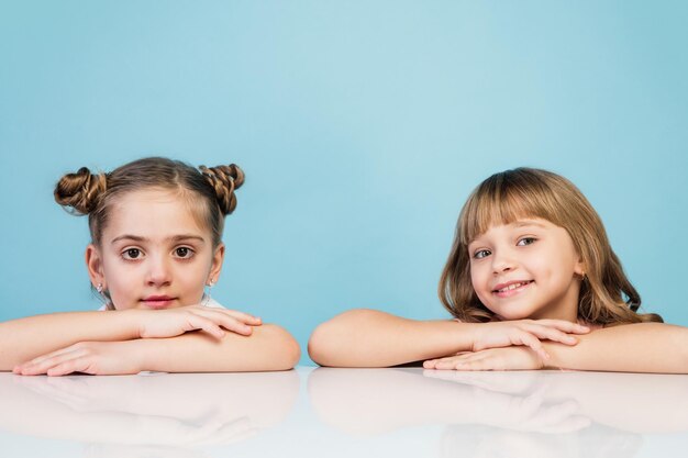 Bambini felici ragazze isolate su sfondo blu studio Guarda felice allegro sincero Copyspace Concetto di emozioni di educazione dell'infanzia