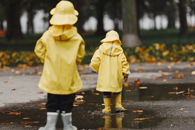 Bambini in un parco d'autunno. Bambini in impermeabili gialli. Persone che si divertono all'aperto.