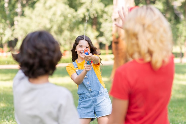 Bambini nel parco a giocare con la pistola ad acqua