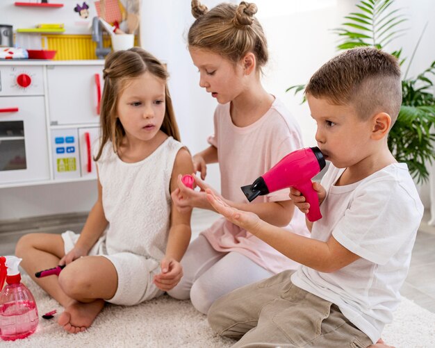 Bambini non binari che giocano insieme a un gioco di salone di bellezza