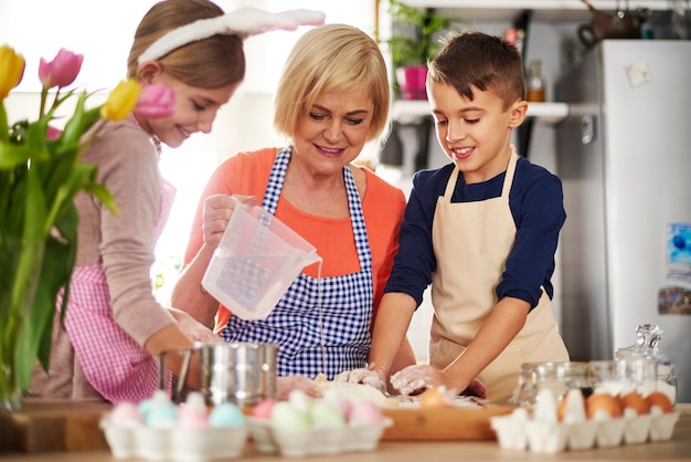 Bambini piccoli che aiutano la nonna con la pasticceria