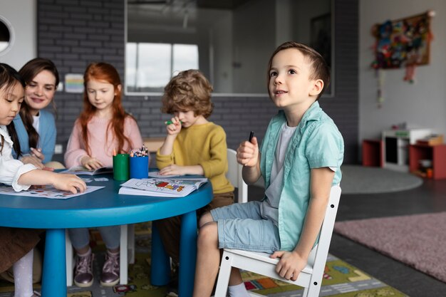 Bambini sorridenti seduti insieme alla vista laterale del tavolo