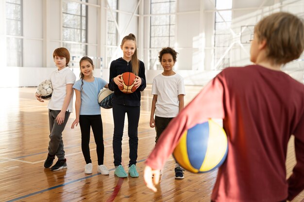 Bambini sportivi che tengono le palle in palestra
