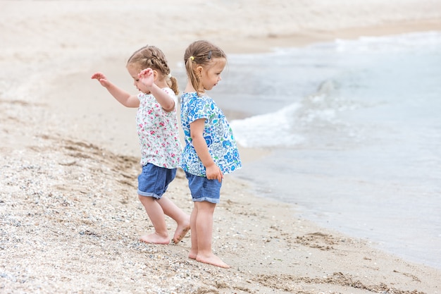 Bambini sulla spiaggia del mare. Gemelli che costeggiano l'acqua di mare.