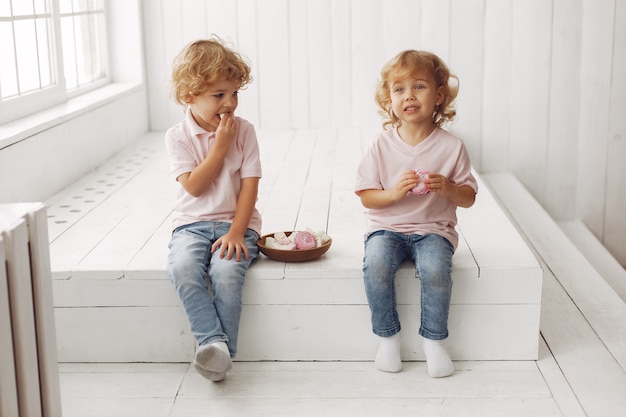 Bambini svegli che mangiano i biscotti a casa