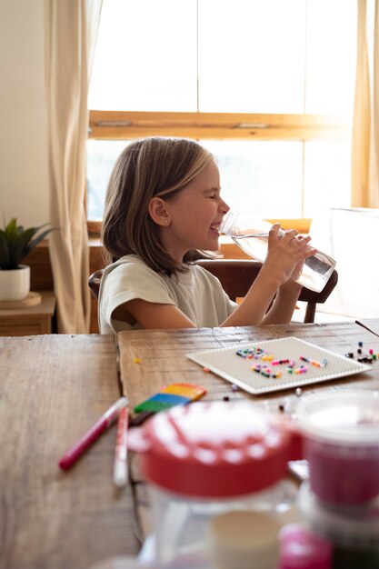 Bambino a tiro medio che beve acqua dalla bottiglia