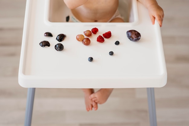 Bambino ad alto angolo nel seggiolone scegliendo quale frutta mangiare