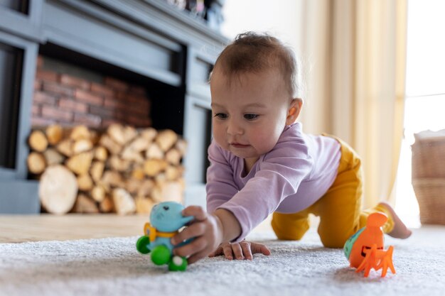 Bambino adorabile che gioca con il giocattolo a casa sul pavimento