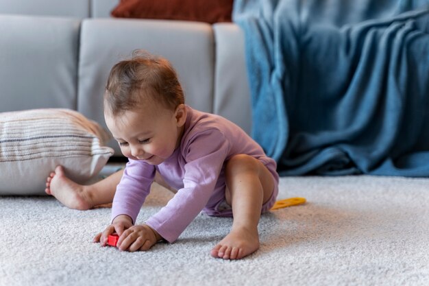 Bambino adorabile che gioca con il giocattolo sul pavimento