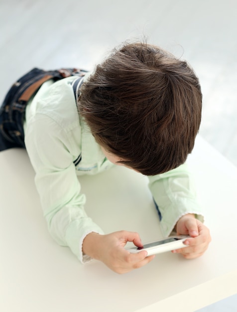 Bambino adorabile che gioca con uno smartphone