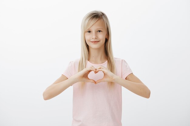 Bambino adorabile che mostra gesto del cuore e sorridere