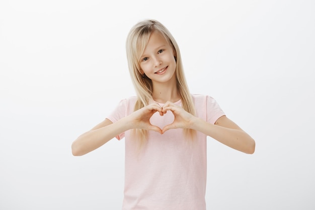 Bambino adorabile che mostra gesto del cuore e sorridere