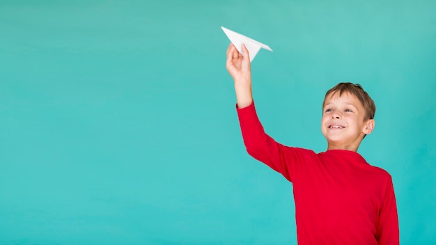 Bambino adorabile che tiene un aeroplano di carta con lo spazio della copia