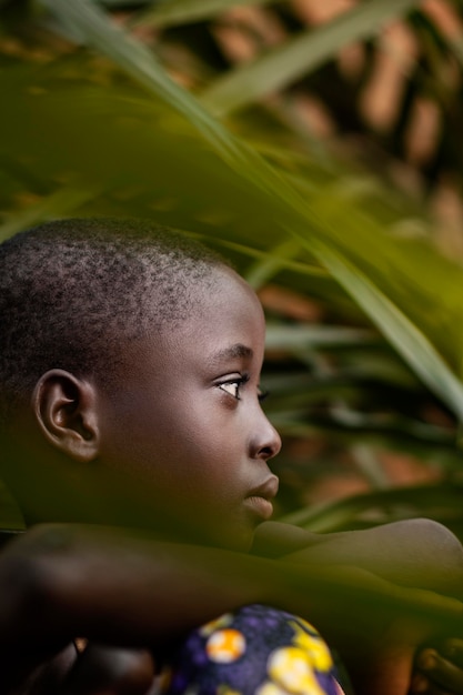 Bambino africano del primo piano che posa con le foglie